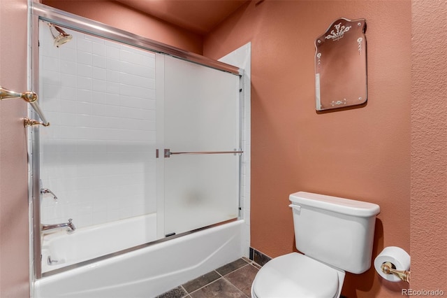 bathroom featuring shower / bath combination with glass door, tile patterned flooring, and toilet