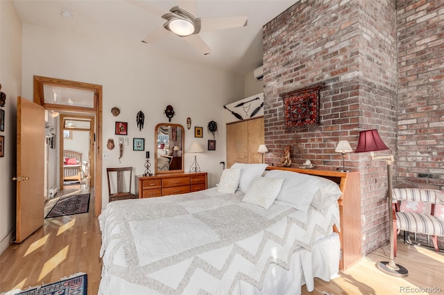 bedroom featuring ceiling fan, brick wall, and light hardwood / wood-style floors