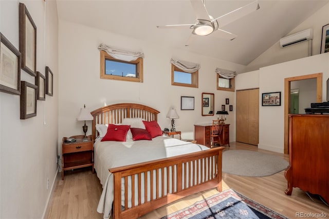 bedroom with ceiling fan, a closet, an AC wall unit, vaulted ceiling, and light hardwood / wood-style flooring