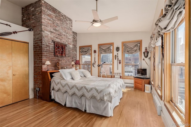 bedroom featuring vaulted ceiling, light hardwood / wood-style flooring, multiple windows, and ceiling fan