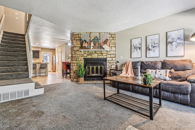12059 E Hoye Dr, Aurora, CO 80012 - carpeted living room with stairs, a stone fireplace, a textured ceiling, and tile patterned floors