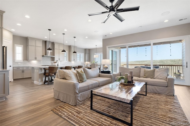 living room featuring ceiling fan, light wood-type flooring, and plenty of natural light