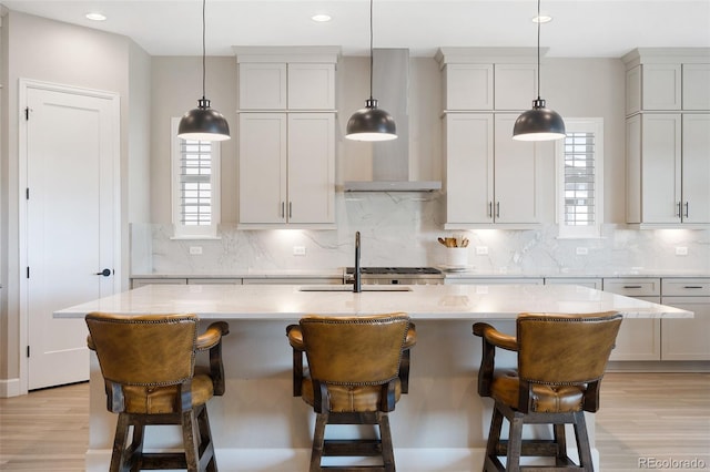 kitchen with a center island with sink, decorative backsplash, sink, and light hardwood / wood-style flooring