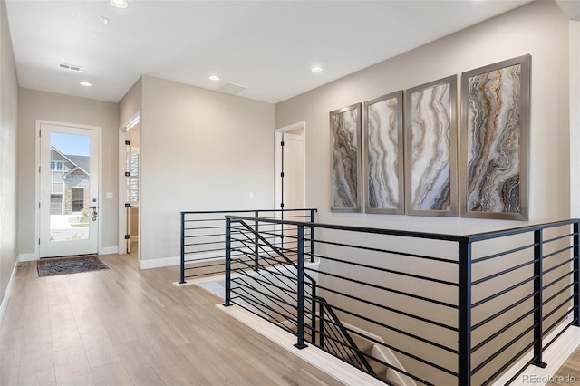 corridor featuring recessed lighting, visible vents, an upstairs landing, wood finished floors, and baseboards