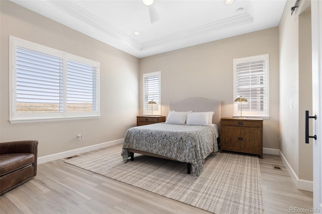 bedroom with ceiling fan, light hardwood / wood-style flooring, and a tray ceiling