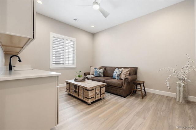 living room featuring ceiling fan, sink, and light hardwood / wood-style floors