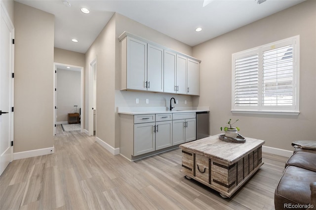 interior space with light hardwood / wood-style floors, gray cabinets, sink, stainless steel dishwasher, and white cabinetry