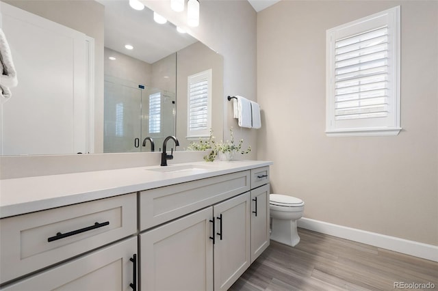 full bathroom with a stall shower, baseboards, toilet, wood finished floors, and vanity