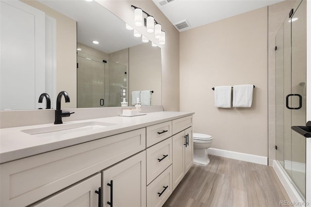 bathroom with wood-type flooring, vanity, toilet, and a shower with shower door