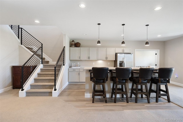 kitchen featuring pendant lighting, white cabinetry, a kitchen island, and stainless steel refrigerator with ice dispenser