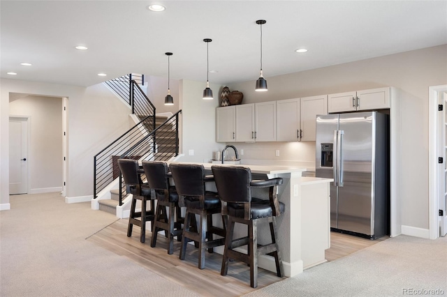 kitchen with light carpet, stainless steel fridge, hanging light fixtures, light countertops, and recessed lighting