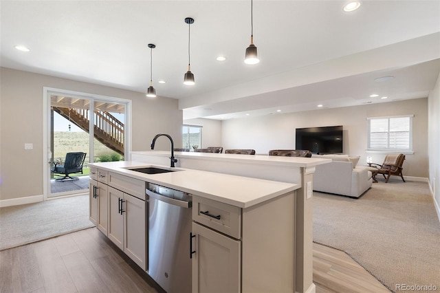 kitchen featuring pendant lighting, an island with sink, light hardwood / wood-style flooring, and stainless steel dishwasher