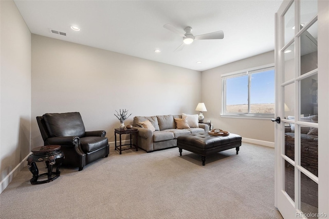 carpeted living room with ceiling fan and french doors