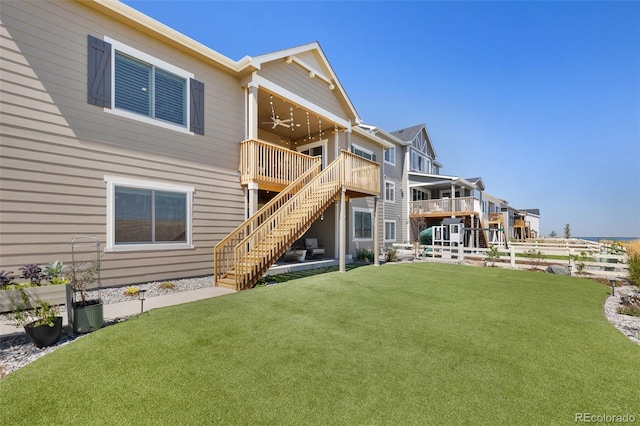 rear view of house with ceiling fan, a wooden deck, and a lawn