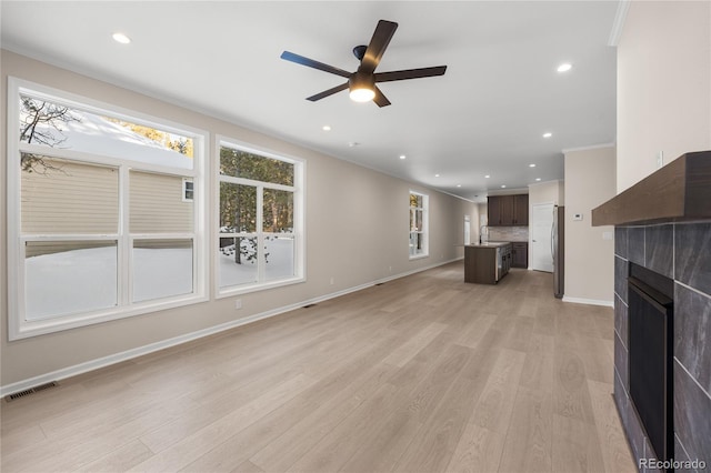 unfurnished living room with ceiling fan, crown molding, light hardwood / wood-style floors, and sink