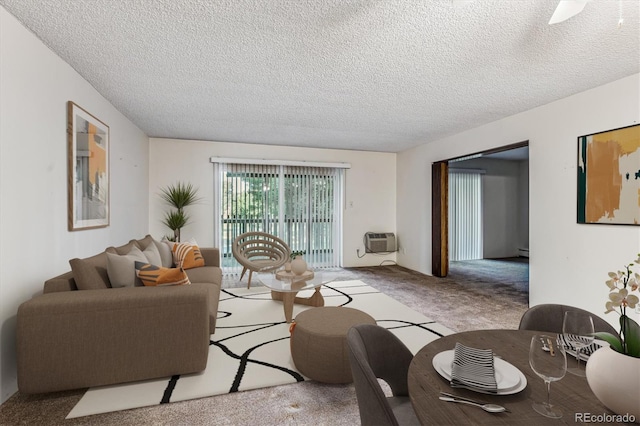 living room with an AC wall unit, a textured ceiling, and light colored carpet