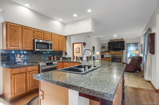 6112 Alkire Ct, Arvada, CO 80004 - kitchen with stainless steel appliances, tile countertops, a fireplace, tasteful backsplash, and open floor plan
