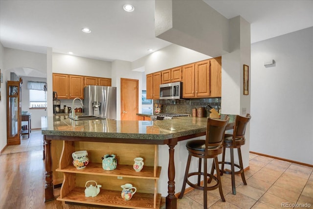 6112 Alkire Ct, Arvada, CO 80004 - kitchen with appliances with stainless steel finishes, open shelves, decorative backsplash, arched walkways, and a peninsula