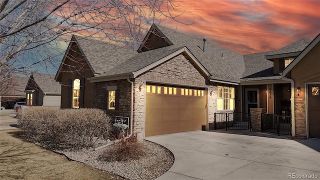 view of front of home with an attached garage, stone siding, a shingled roof, and concrete driveway