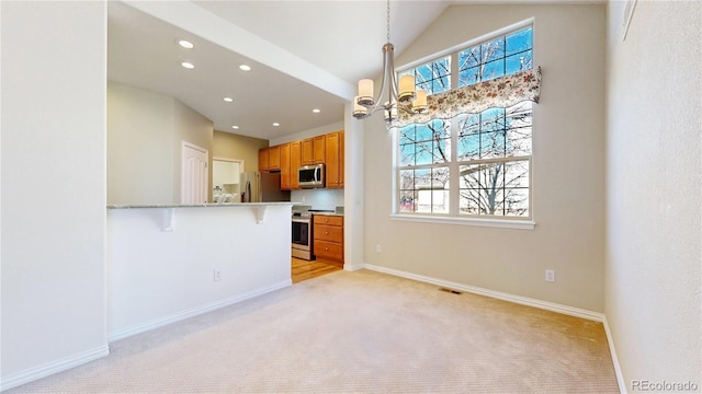 kitchen with appliances with stainless steel finishes, a healthy amount of sunlight, a notable chandelier, and a breakfast bar area