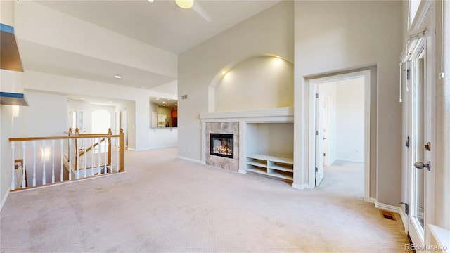 unfurnished living room with baseboards, high vaulted ceiling, carpet flooring, and a tile fireplace