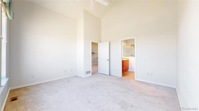 unfurnished bedroom with light carpet, a towering ceiling, visible vents, and baseboards