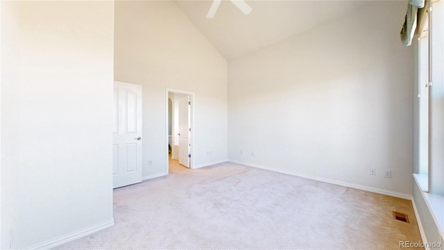 spare room with high vaulted ceiling, light colored carpet, visible vents, and baseboards