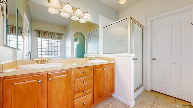 full bathroom featuring double vanity, a stall shower, a sink, and tile patterned floors