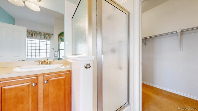 bathroom featuring a stall shower, a spacious closet, and vanity