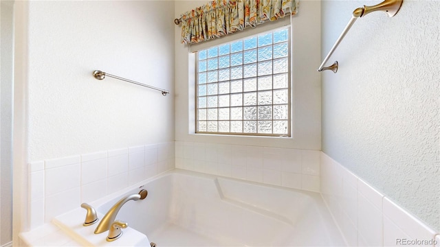 full bathroom featuring a textured wall, a garden tub, and a healthy amount of sunlight