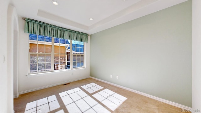 carpeted spare room featuring baseboards, visible vents, a tray ceiling, and recessed lighting