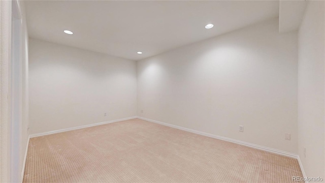 spare room with baseboards, recessed lighting, and light colored carpet