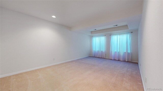 empty room featuring light carpet, visible vents, baseboards, a tray ceiling, and recessed lighting