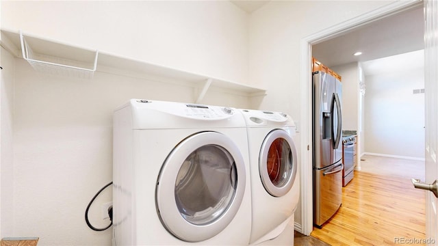 washroom featuring light wood-style floors, washing machine and dryer, laundry area, and baseboards