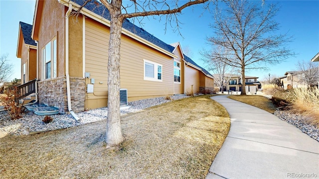 view of home's exterior with stone siding, a lawn, and stucco siding