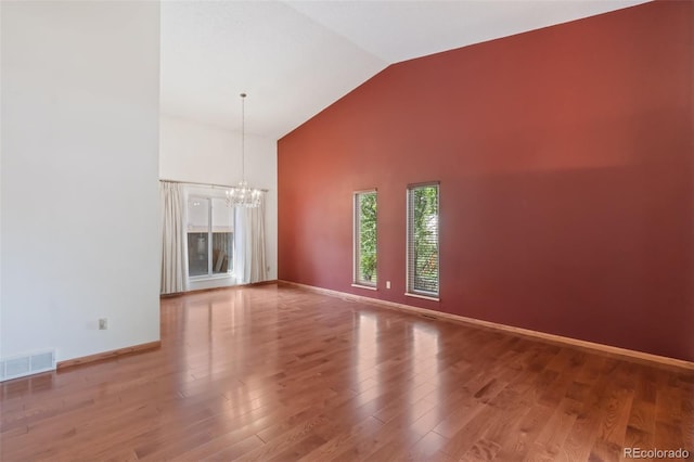 unfurnished living room with an inviting chandelier, hardwood / wood-style floors, and high vaulted ceiling