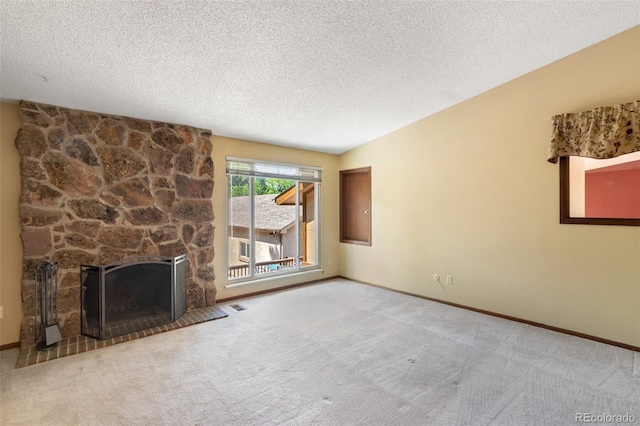 unfurnished living room featuring carpet floors, a stone fireplace, and a textured ceiling