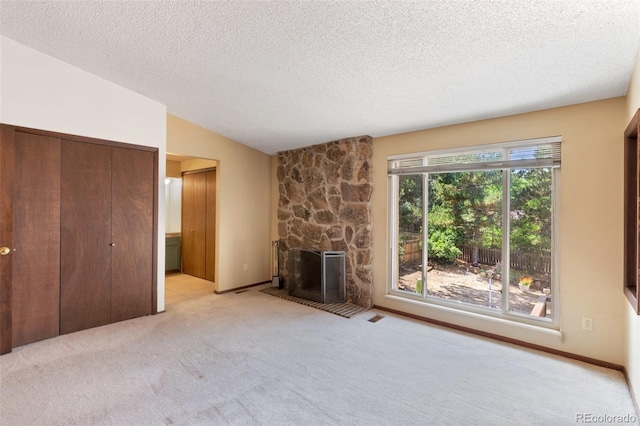 unfurnished living room featuring a textured ceiling, a fireplace, vaulted ceiling, and light carpet