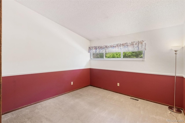 empty room with light carpet and a textured ceiling