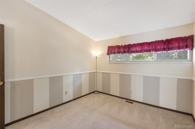 unfurnished room with carpet floors, a textured ceiling, and vaulted ceiling