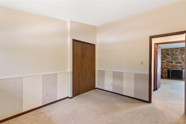 carpeted spare room with a textured ceiling and a fireplace