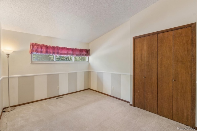 unfurnished bedroom with light colored carpet, a textured ceiling, and a closet