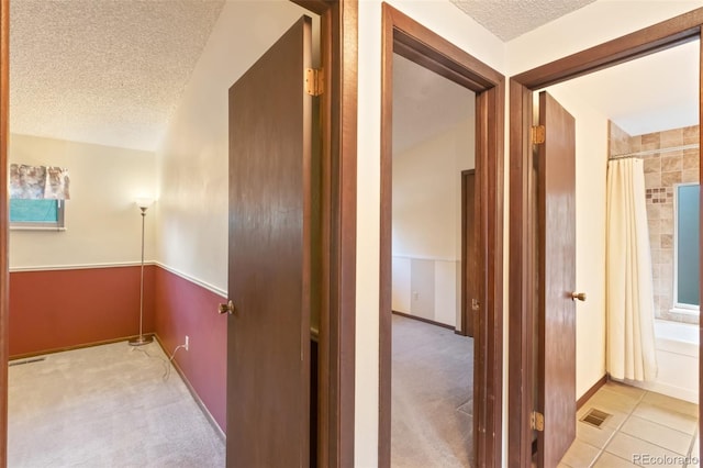 corridor featuring a textured ceiling and light colored carpet