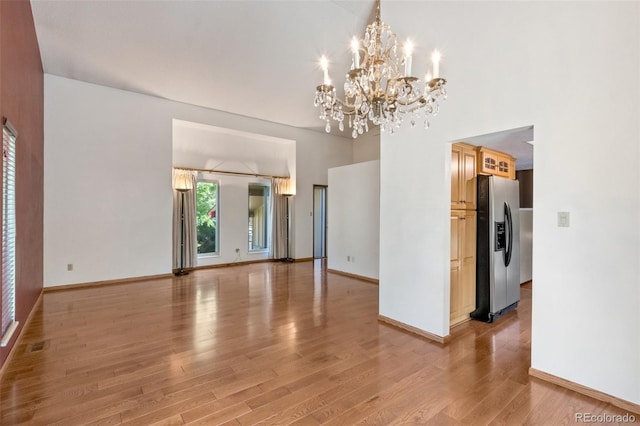 unfurnished room featuring an inviting chandelier and light hardwood / wood-style flooring