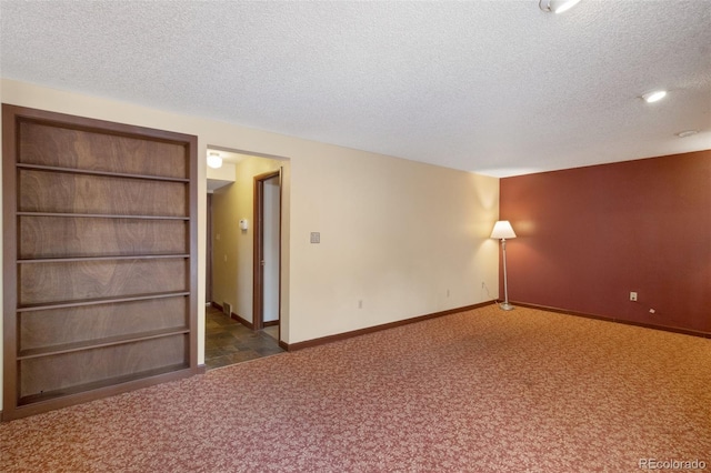 unfurnished room with a textured ceiling and dark colored carpet