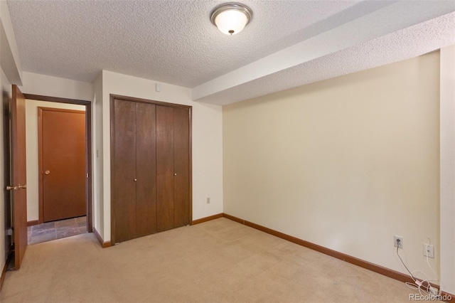 unfurnished bedroom with a textured ceiling, light carpet, and a closet