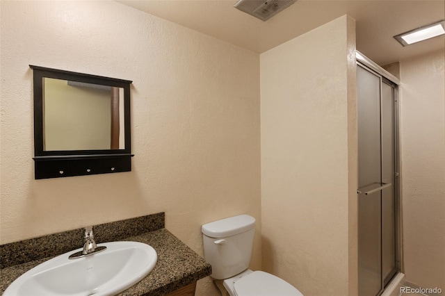 bathroom featuring vanity, toilet, and an enclosed shower