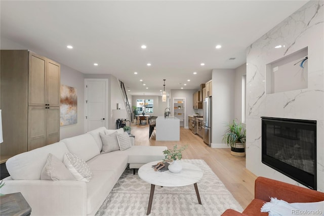 living room featuring a premium fireplace, sink, and light hardwood / wood-style floors