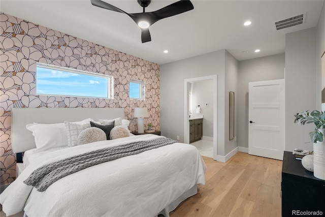 bedroom with ceiling fan, connected bathroom, and light hardwood / wood-style flooring