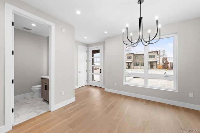 unfurnished dining area with light wood-type flooring and an inviting chandelier